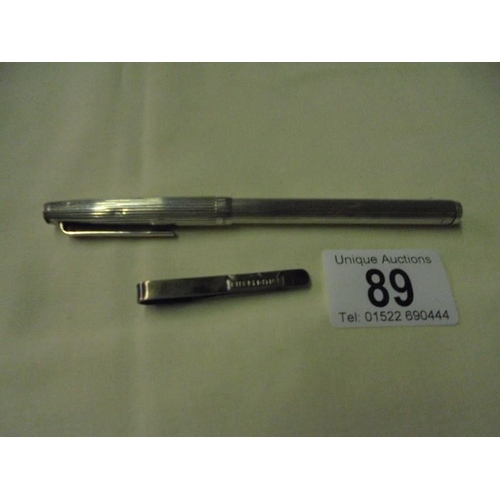89 - A silver ball point pen and a silver paper clip.