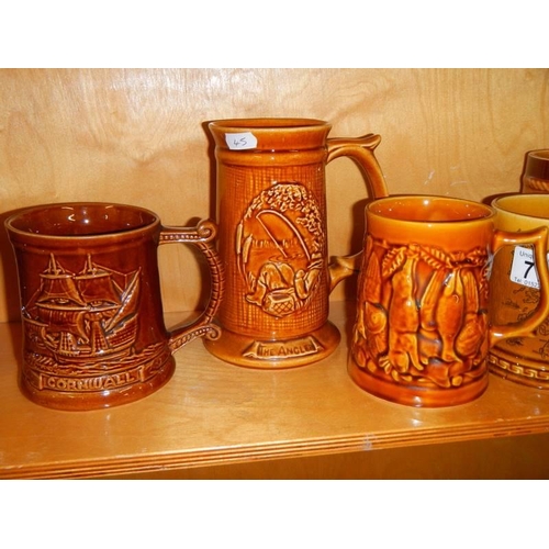 711 - A quantity of brown glazed souvenir tankards including Jamaica Inn, Jersey and Scotland.