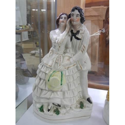 827 - A 19th century Staffordshire figure of a young couple and one other, (one a/f)