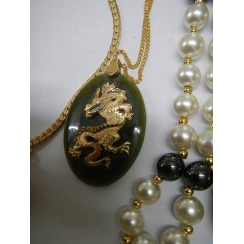 955 - A selection of necklaces including a jade dragon pendant.