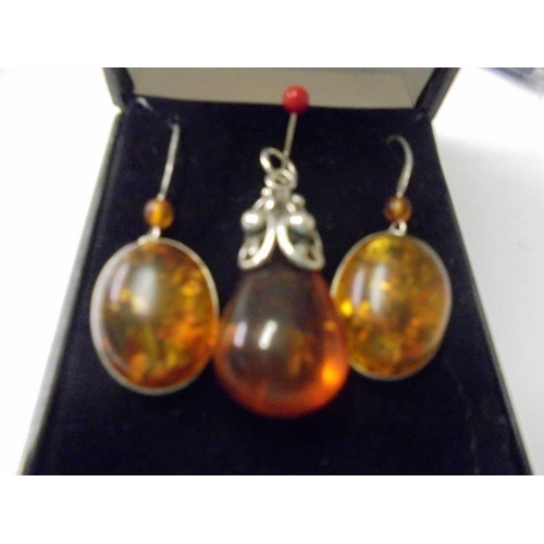 135 - An amber pendant in silver together with amber drop earrings in silver.