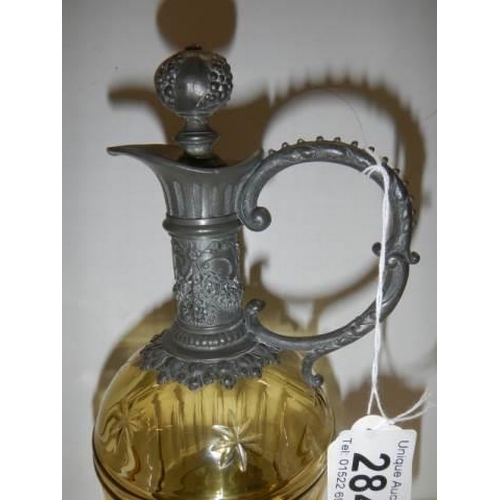 284 - A glass and metal claret jug with two glasses.