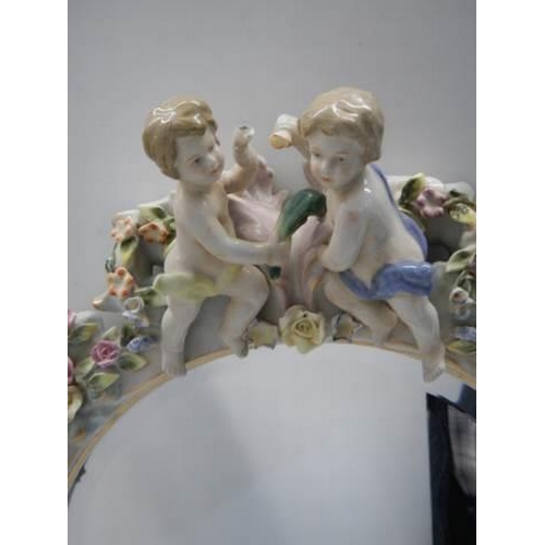 319 - A 20th century porcelain framed mirror with cherubs and flowers, COLLECT ONLY.