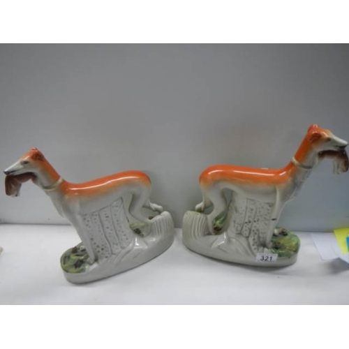 321 - A pair of 19th century Staffordshire greyhounds with hares in mouths, 28.2 cm tall.