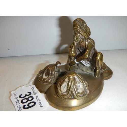 389 - An antique brass figure of a snake charmer.