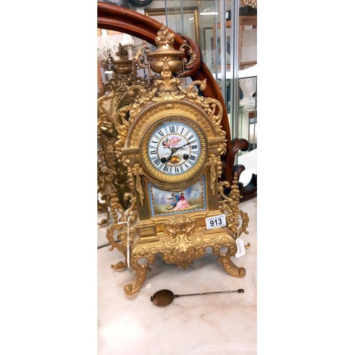 913 - A French ormolu mantel clock with enamel dial and porcelain panel.