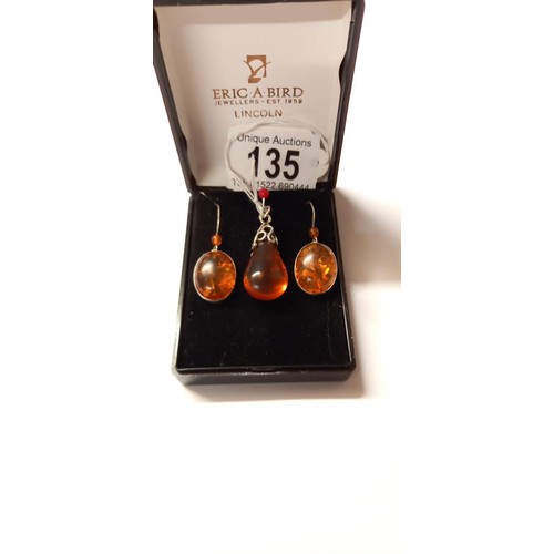 135 - An amber pendant in silver together with amber drop earrings in silver.