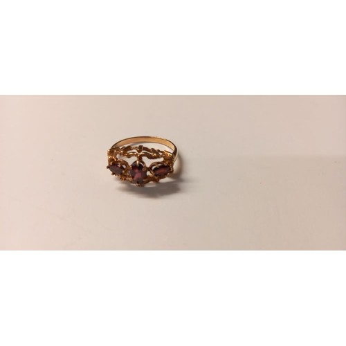 150B - A three stone ring set with oval garnets in a textured mount gold shank, size P, 2.8 grams.