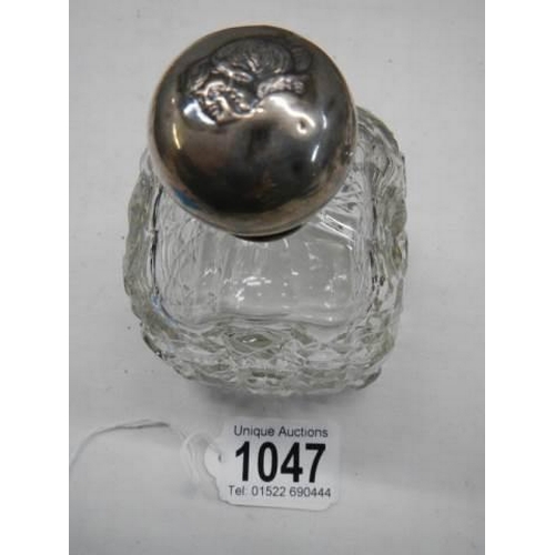 1047 - A hobnail cut glass bottle with silver top embosses with two heads.