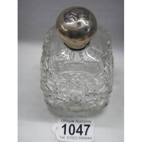 1047 - A hobnail cut glass bottle with silver top embosses with two heads.