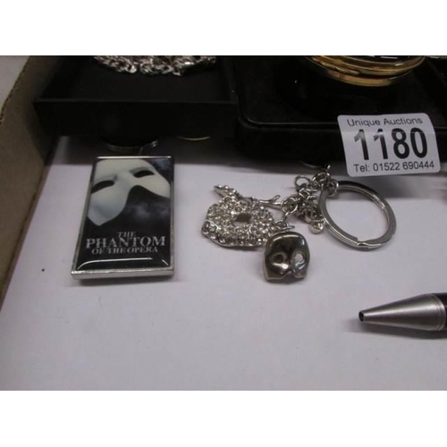 1180 - A silver Phantom mask necklace, enamel box, charm bracelet, pin badges etc.,