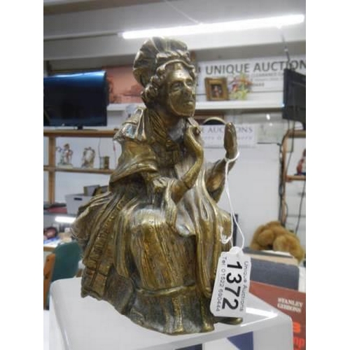 1372 - An early brass figure of an elderly lady.