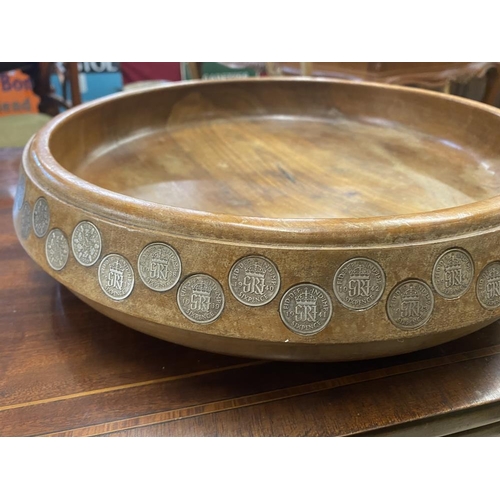 1100E - A large teak fruit bowl inlaid with sixpences in numerical order from 1909-1964 along with Latin ins... 