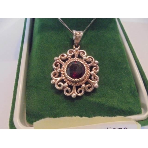 1026 - A silver pendant set with garnet stone on a silver chain,