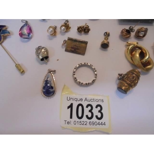 1033 - A mixed lot of earrings and charms including a silver butterfly.