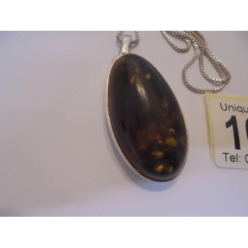 1035 - A large oval amber pendant in silver mount and on silver chain.