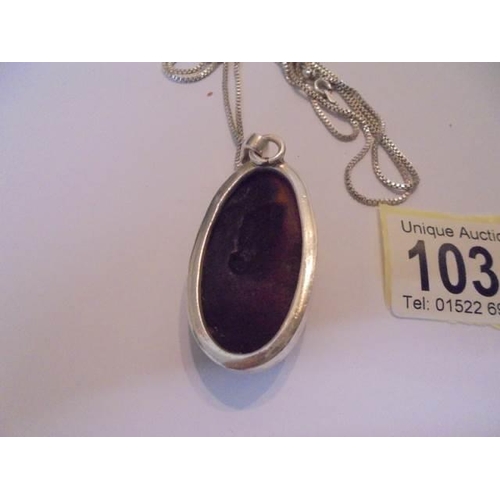 1035 - A large oval amber pendant in silver mount and on silver chain.