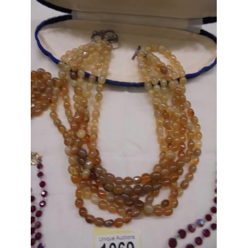 1069 - A six strand yellow stone necklace and a two strand red bead necklace.