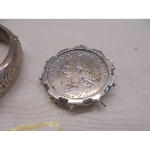 1099 - A silver bangle and a silver Victorian coin brooch.