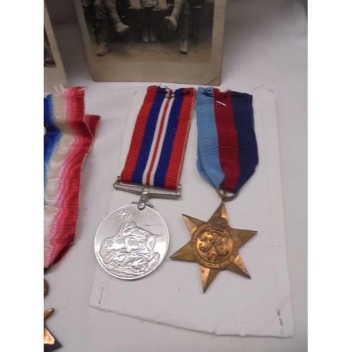 1107 - Three WW1 medals, Two WW2 medals and a quantity of military postcards.