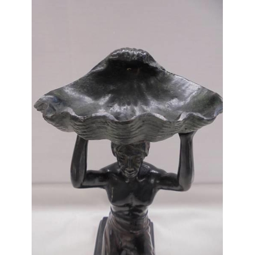 1189 - A bronze figure of a kneeling man holding a large shell above his head.