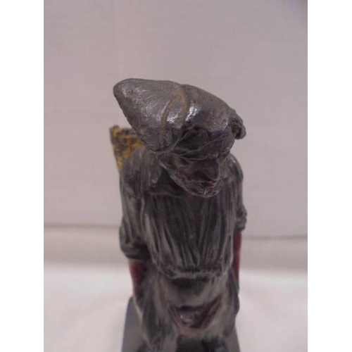 1190 - A painted cast metal figure of a man smoking a cigarette and carrying a basket.