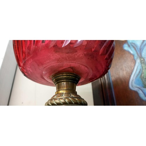 1324 - A brass oil lamp base with cranberry glass font (font a/f, crack to underside).