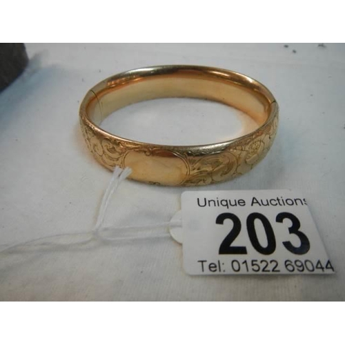 203 - An engraved gold coloured bangle.