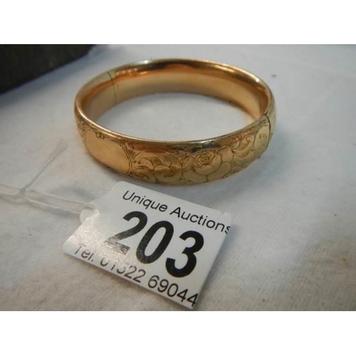 203 - An engraved gold coloured bangle.