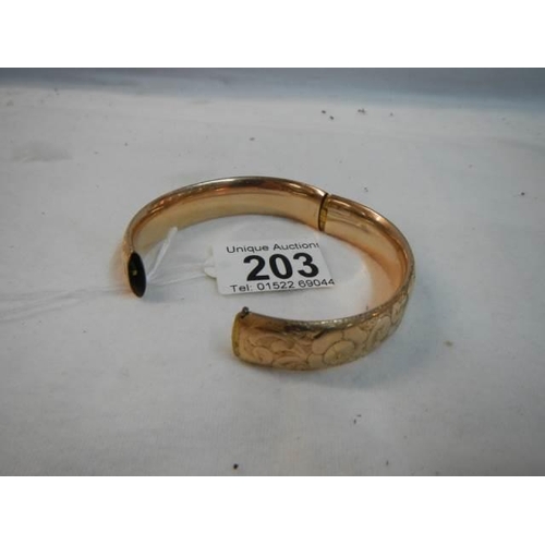 203 - An engraved gold coloured bangle.