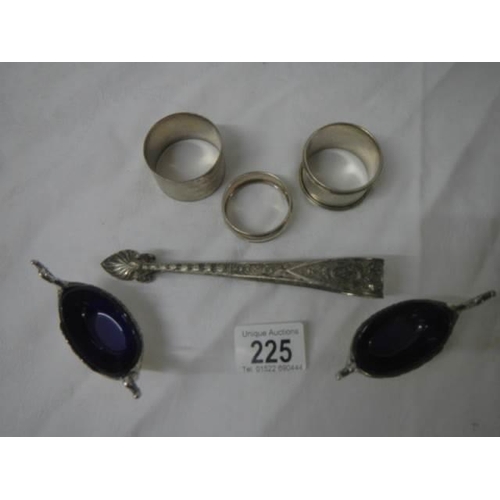 225 - Three silver napkin rings, two plated salts with blue glass linings and a pair of sugar nips.