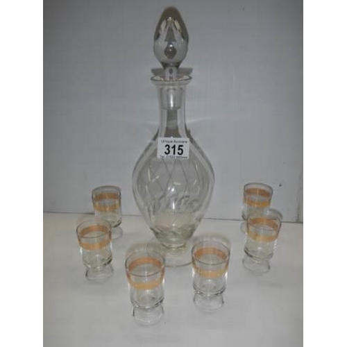 315 - An engraved glass decanter and a set of six gilt rimmed glasses. COLLECT ONLY.