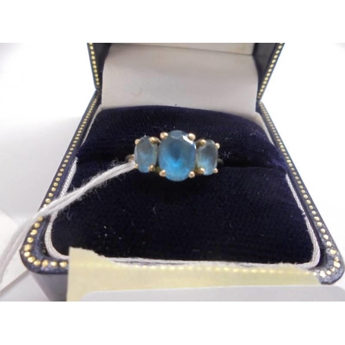 1068 - A 9ct gold ring set three blue stones, size M, 2.6 grams.