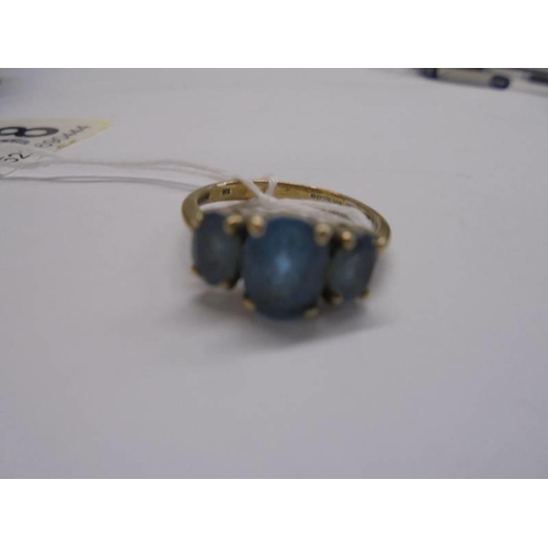 1068 - A 9ct gold ring set three blue stones, size M, 2.6 grams.