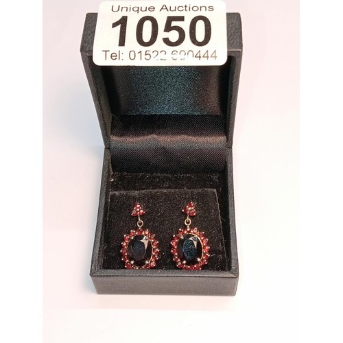 1050 - A pair of 9ct gold earrings set red stones.