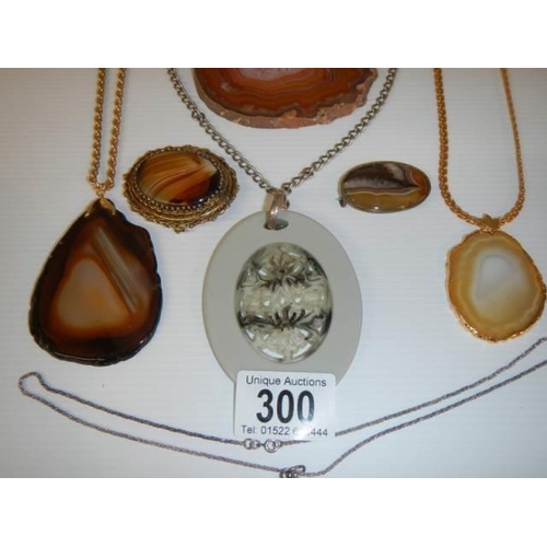 300 - An amber pendant, two agate pendants, two agate brooches etc.,