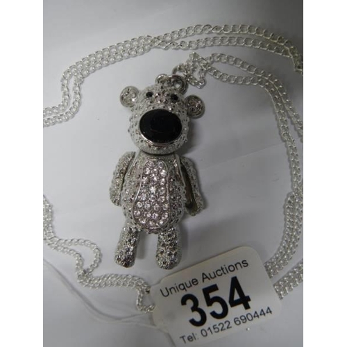 354 - A white metal articulated teddy bear on a long chain.