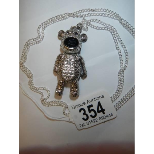 354 - A white metal articulated teddy bear on a long chain.