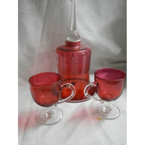 1451 - A Cranberry glass bell and two cranberry glass footed cups.