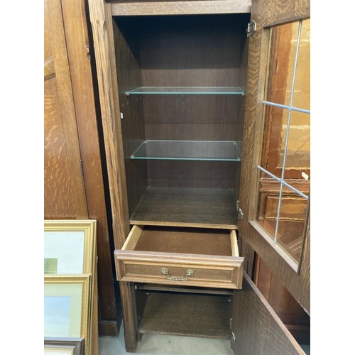 269 - A medium oak effect cupboard with glazed and leaded upper cupboard containing two glass shelves, dra... 