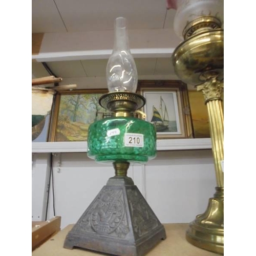 210 - An early 20th century oil lamp on cast iron base with green glass font and chimney. COLLECT ONLY.