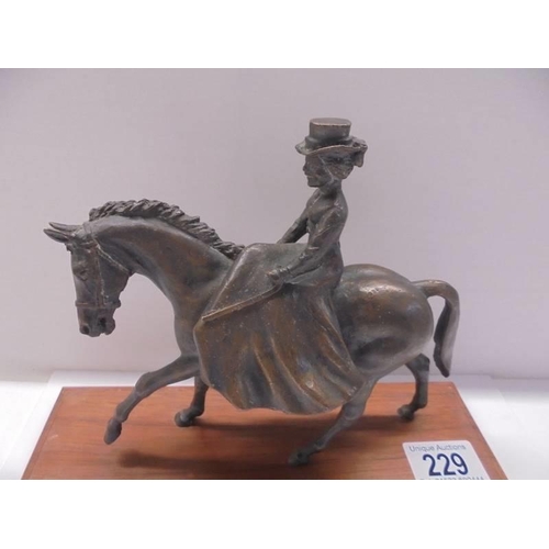 229 - A bronze figure of a lady riding a horse side saddle, length 18cm, height 15.5 cm.