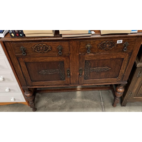 584 - An Oak side board with decorative carving applied to draw and door fronts, trop pulls, turned balust... 