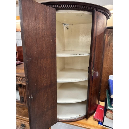 585 - A bow fronted inlaid mahogany hanging corner cupboard with 3 interior shelves lock with key brass es... 