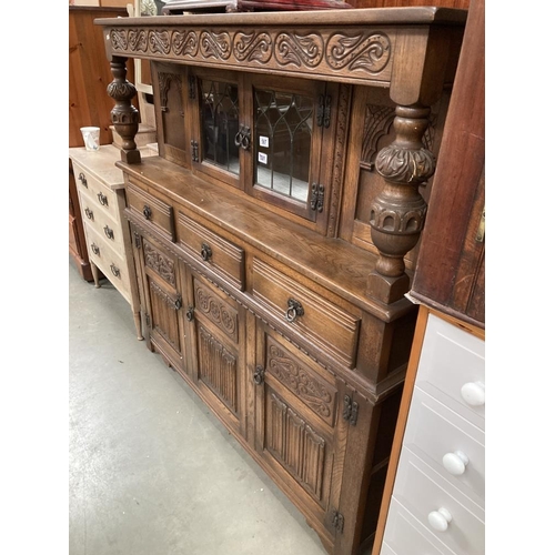 587 - An Oak buffet with carved and decorated detail and turned baluster supports glazed centre doors to t... 