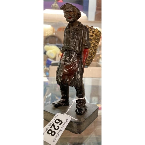 628 - A Cast metal peasant figure carrying a large basket in traditional dress on slate base. Height 17cm