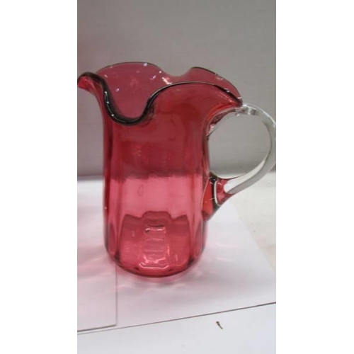 281 - Three cranberry glass jugs.