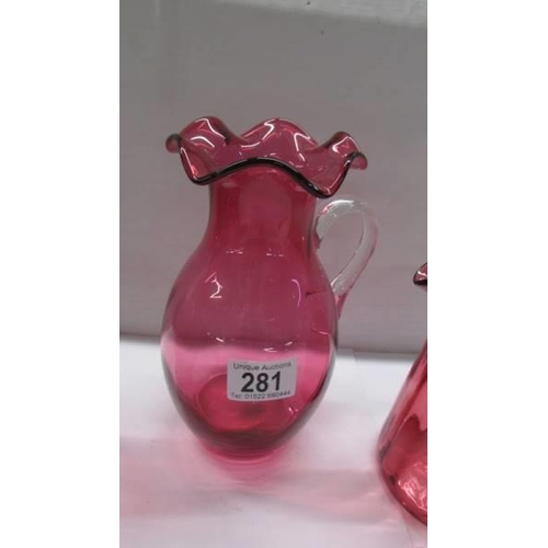 281 - Three cranberry glass jugs.