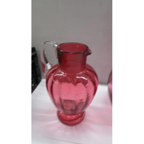 281 - Three cranberry glass jugs.