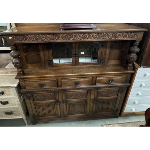 587 - An Oak buffet with carved and decorated detail and turned baluster supports glazed centre doors to t... 